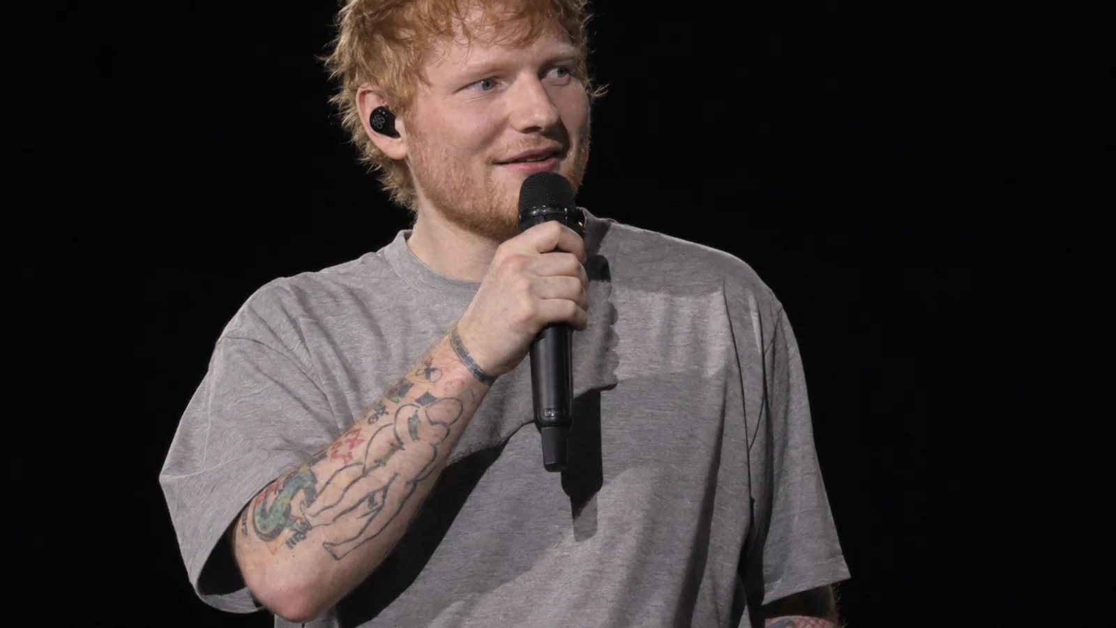 Ed Sheeran performing on a dark concert stage