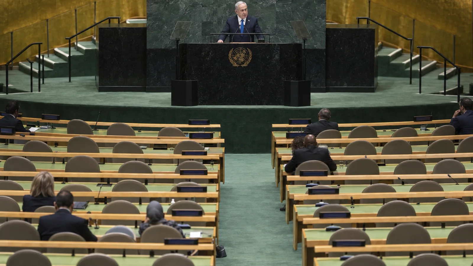 Benjamin Netanyahu speaks at the UN General Assembly podium as many seats in the chamber are empty.